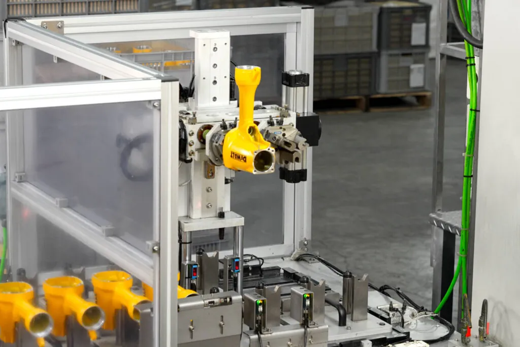 黄色の空圧工具本体に対し±0.01mm精度を達成するための二次CNC加工を行う自動ロボット生産ライン